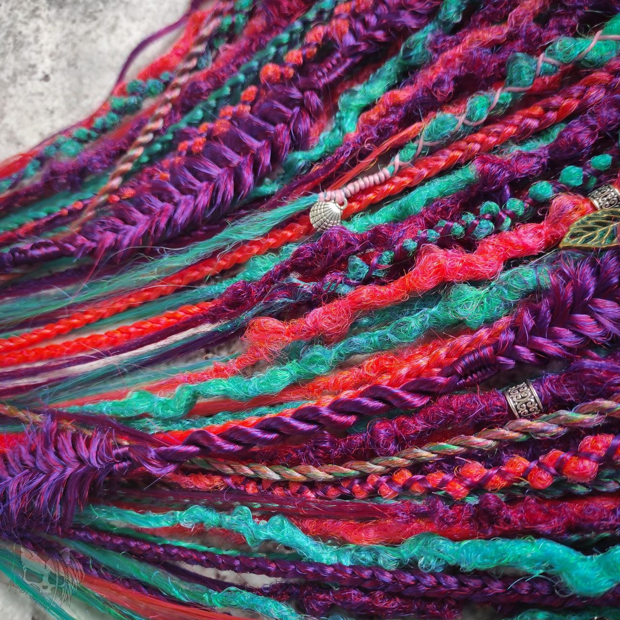 Synthetic dreads with purple transitioning into green and orange, complemented by braids