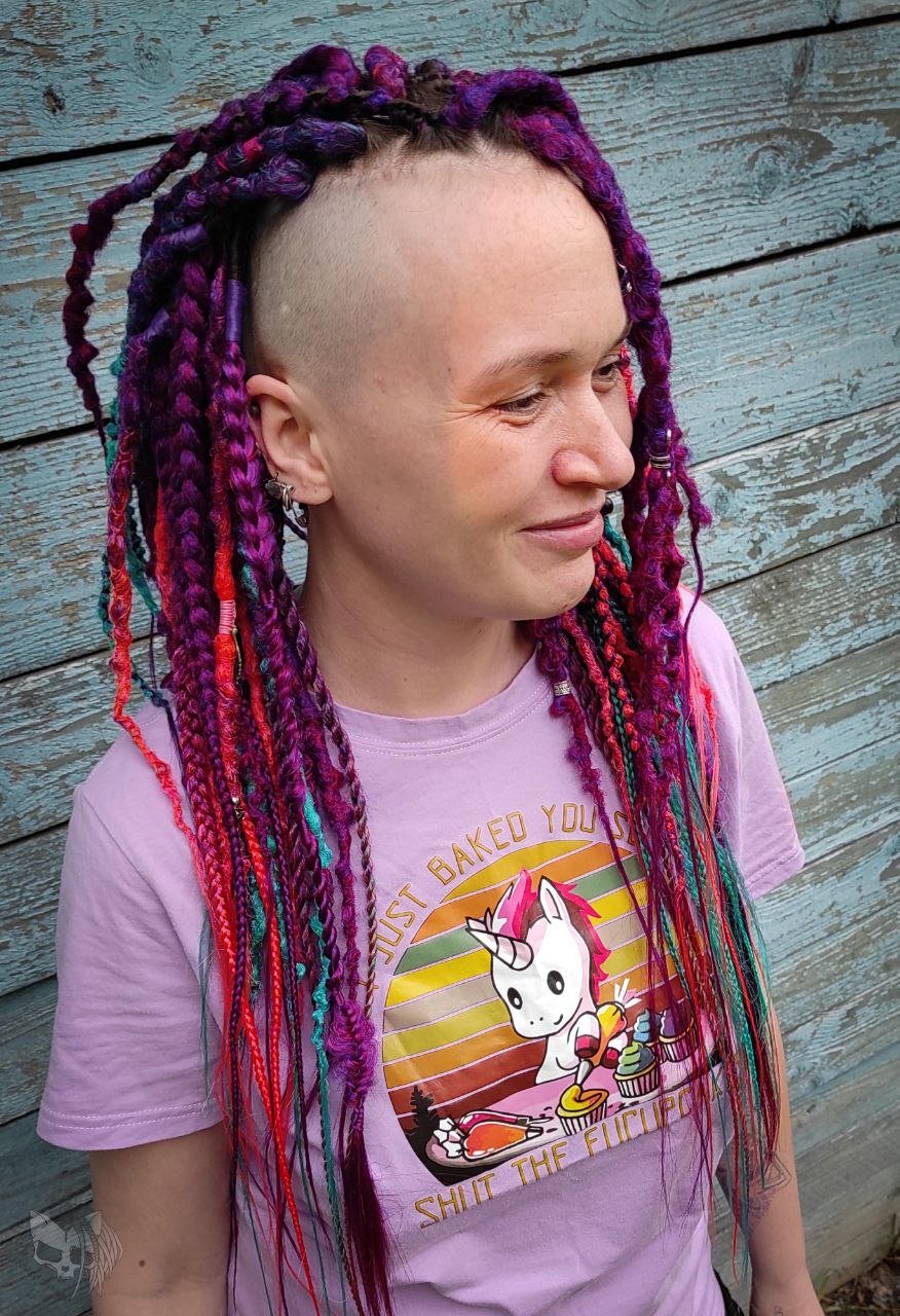 Synthetic dreads with purple transitioning into green and orange, complemented by braids