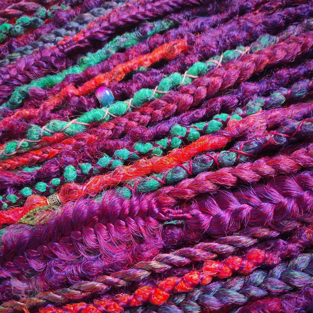 Synthetic dreads with purple transitioning into green and orange, complemented by braids