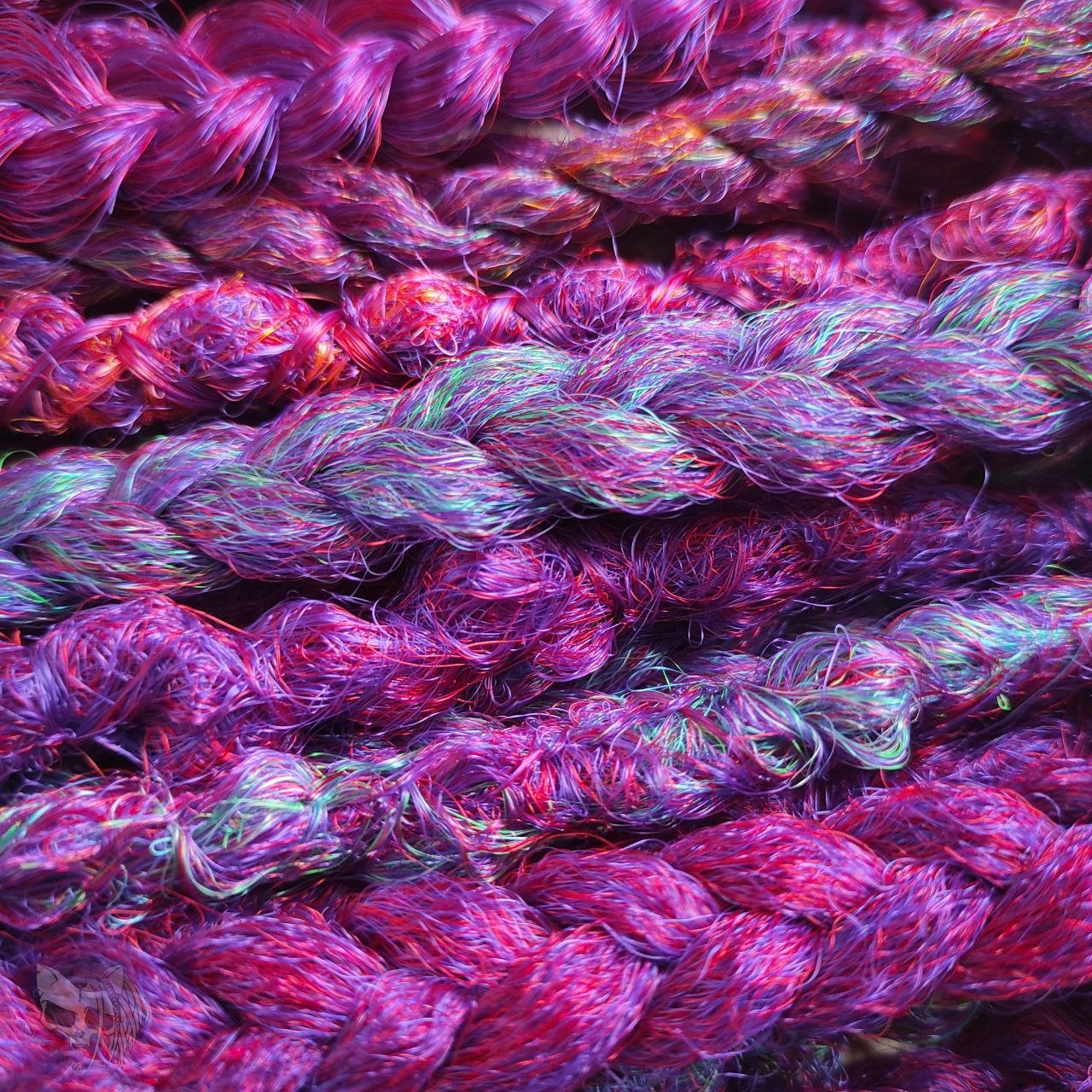 Synthetic dreads with purple transitioning into green and orange, complemented by braids