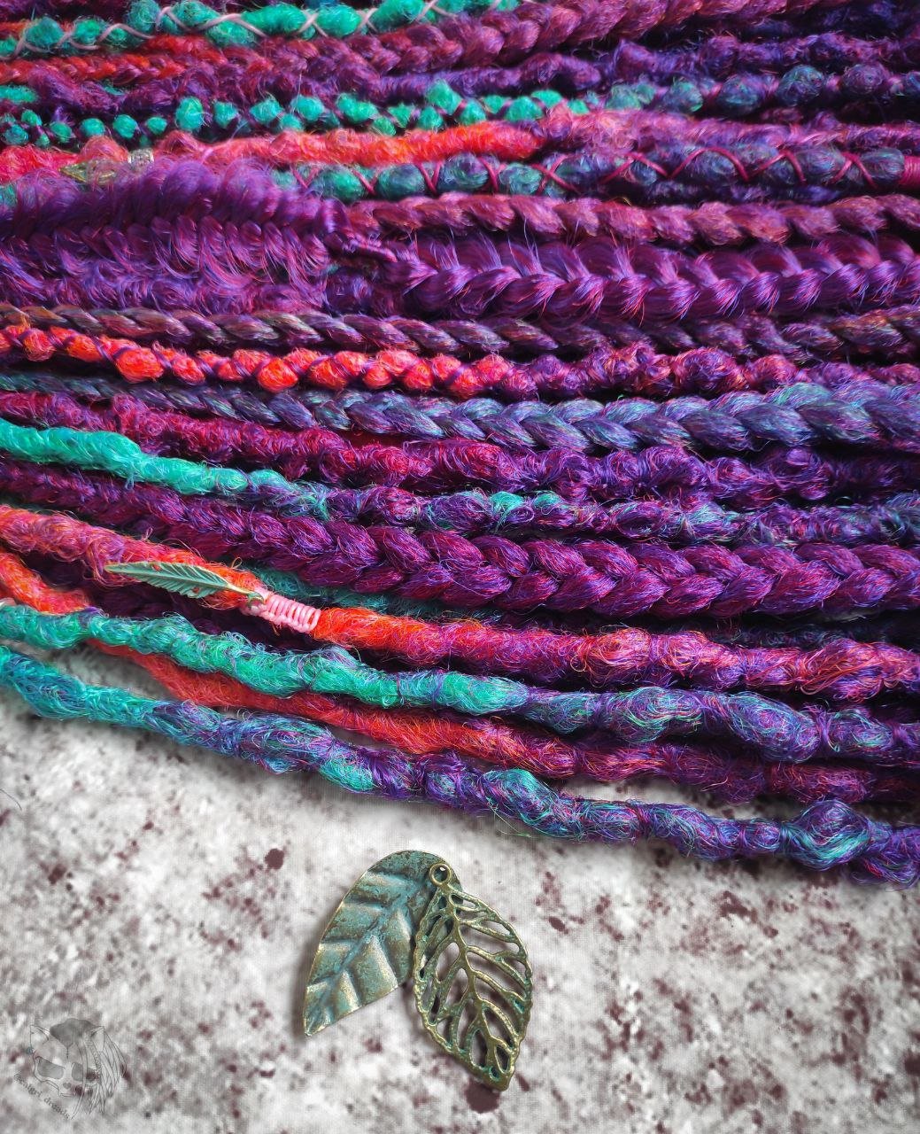 Synthetic dreads with purple transitioning into green and orange, complemented by braids