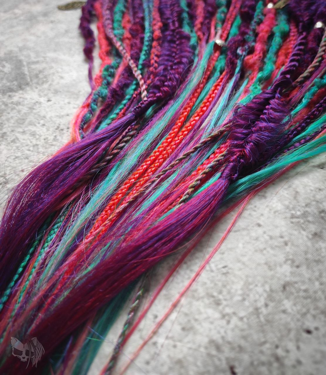 Synthetic dreads with purple transitioning into green and orange, complemented by braids