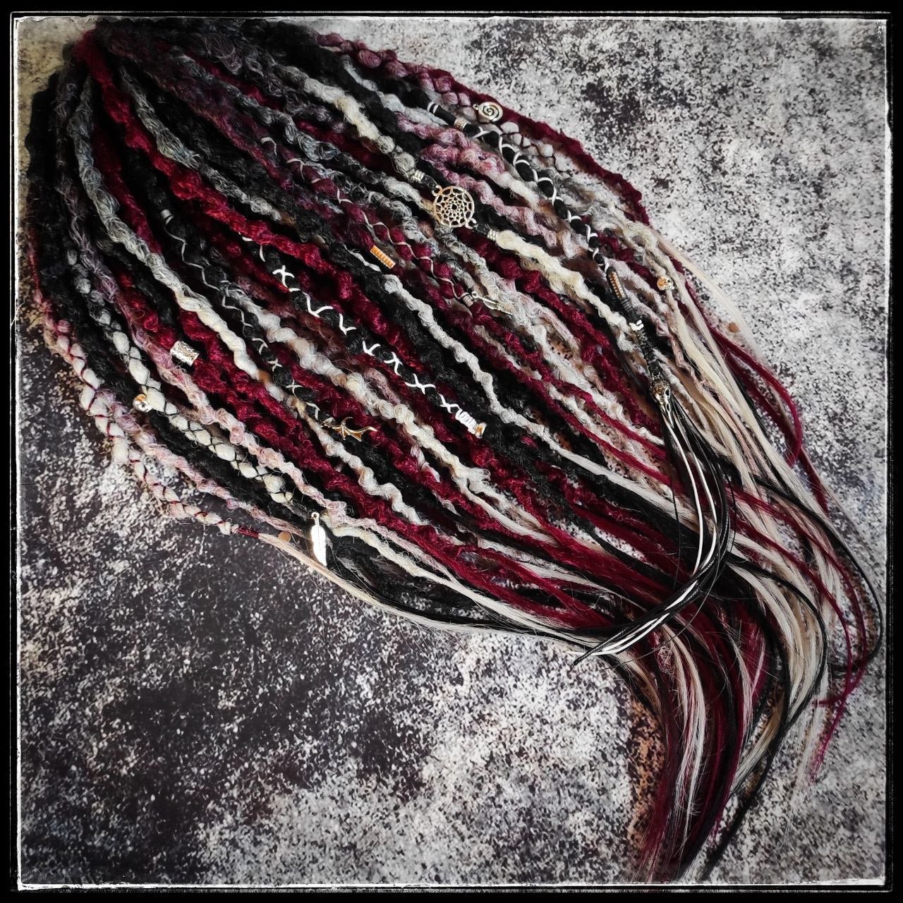 Solid black synthetic dreads transitioning into a red and grey ombre, available in a set of 30 double-ended dreads