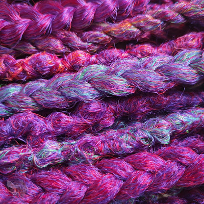 Synthetic dreads with purple transitioning into green and orange, complemented by braids