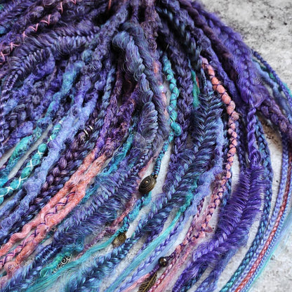 Purple synthetic dreads featuring brown-to-pink, turquoise, and blue ombre extensions, along with braids
