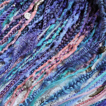 Synthetic dreads in purple, featuring ombre extensions transitioning from brown to pink, turquoise, and blue, along with braids