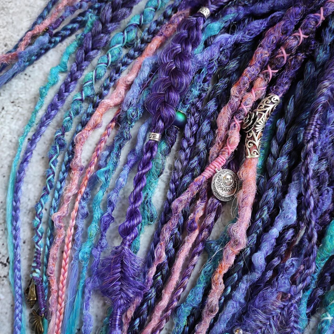 Synthetic dreads in purple, featuring ombre extensions transitioning from brown to pink, turquoise, and blue, along with braids