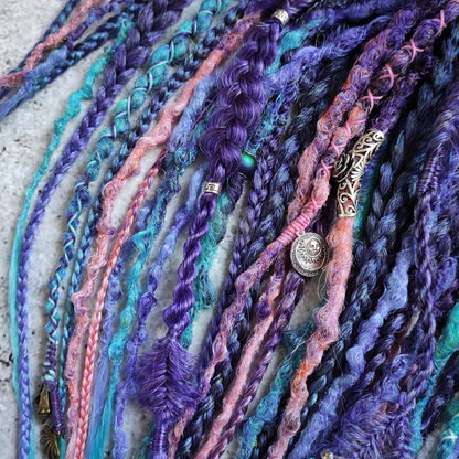 Synthetic dreads in purple, featuring ombre extensions transitioning from brown to pink, turquoise, and blue, along with braids