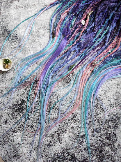 Synthetic dreads in purple, featuring ombre extensions transitioning from brown to pink, turquoise, and blue, along with braids
